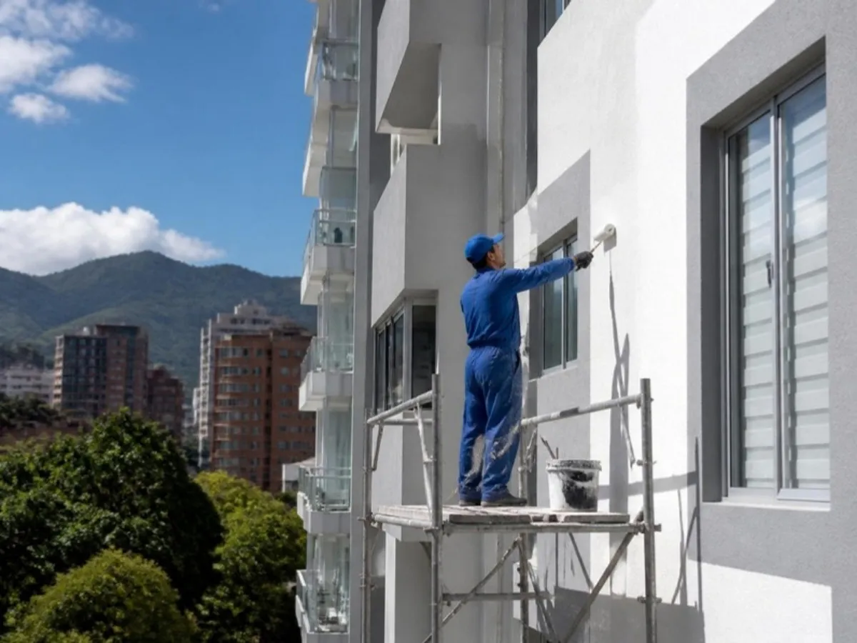Pintor en andamio realizando mantenimiento de fachada en Bogotá